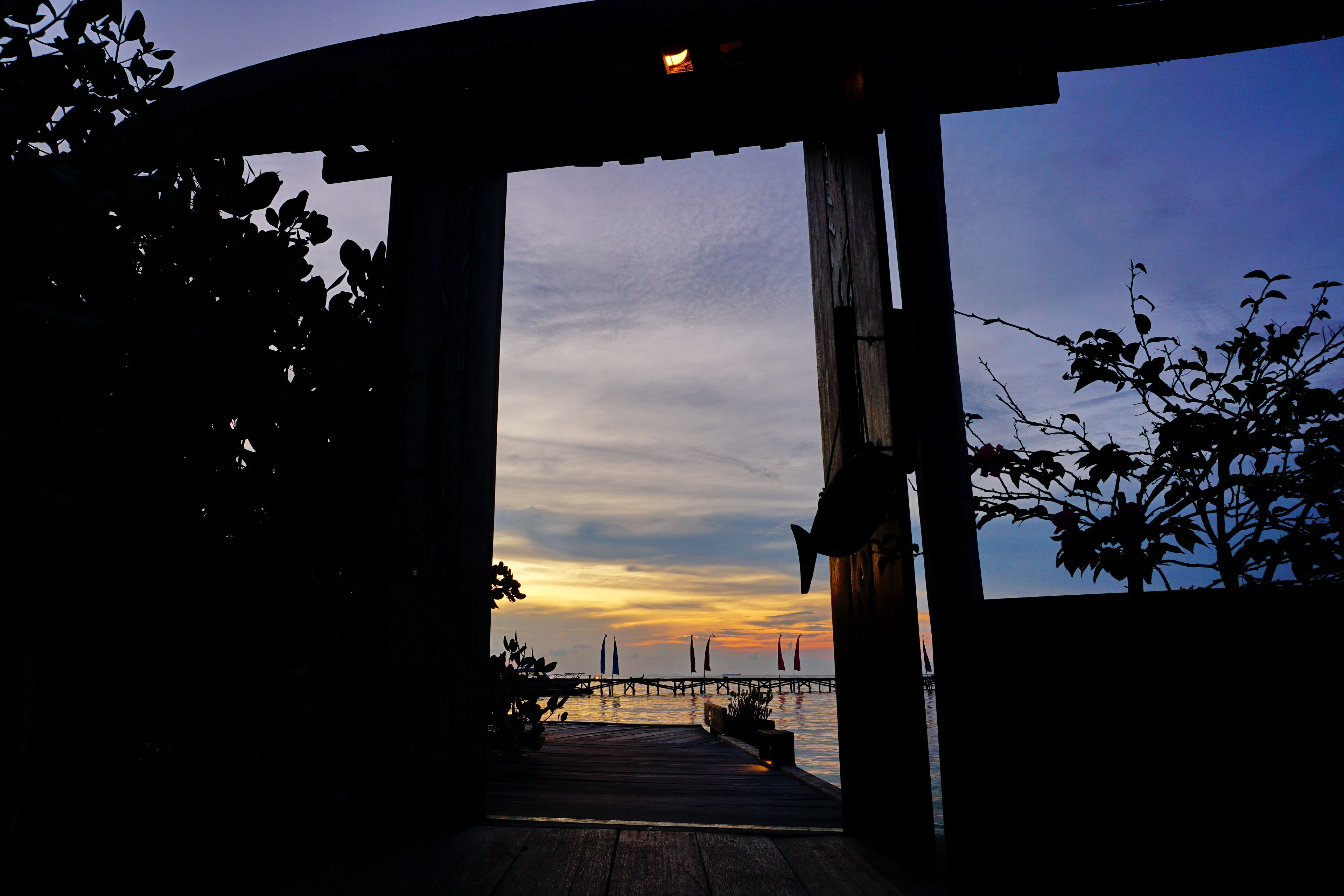 A wooden pier extending into a body of water with a sunset in the background.