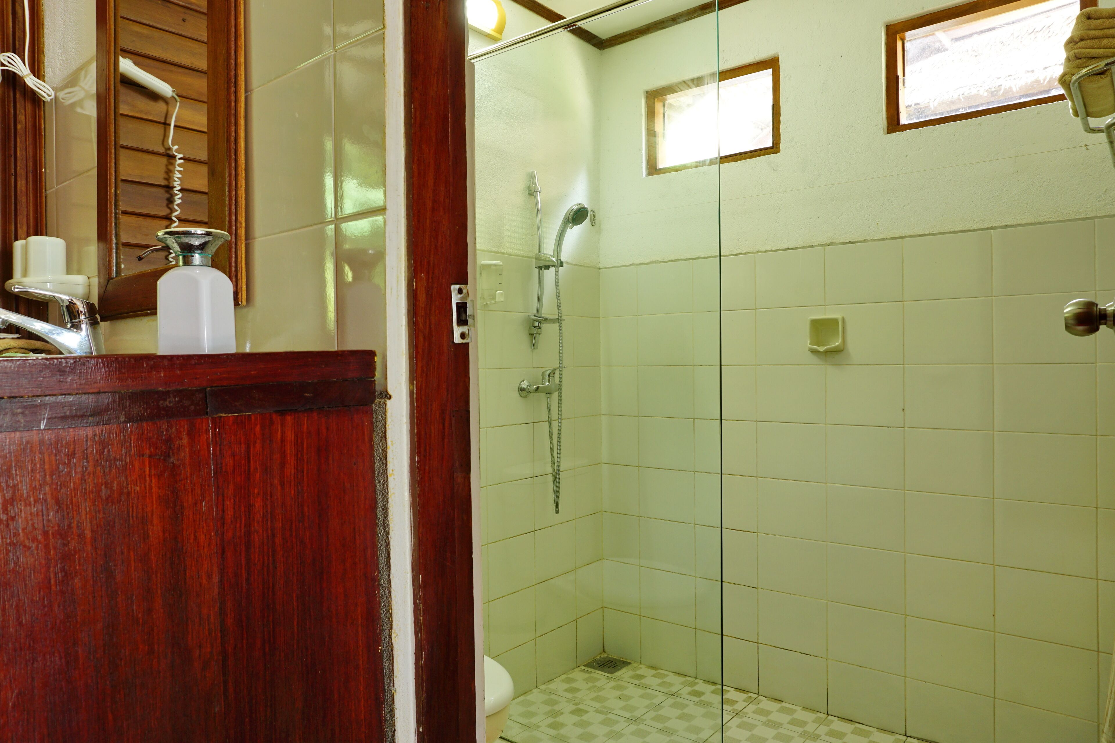 A bathroom with a wooden vanity, a shower with a glass door, and a toilet.