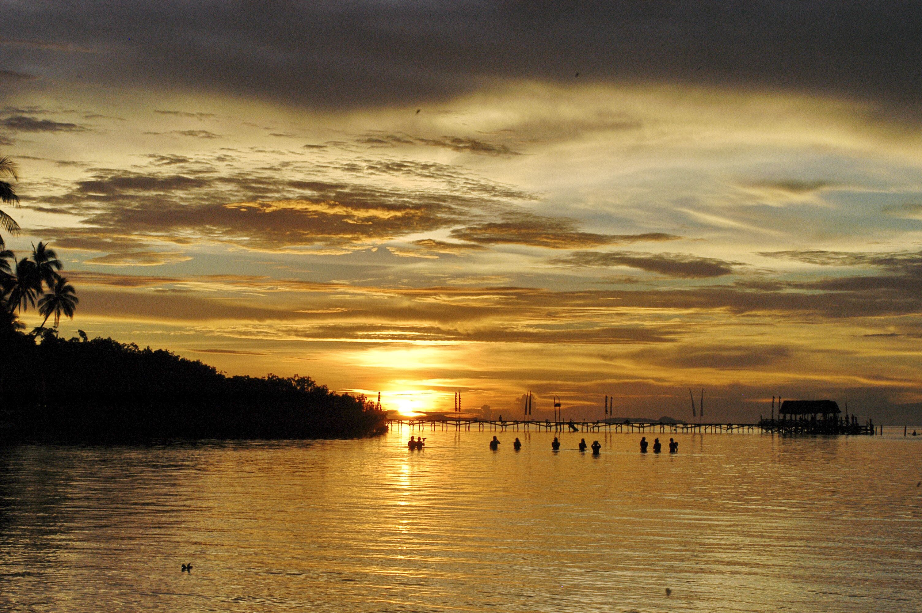 A sunset over a calm body of water with a pier extending into the water.
