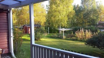 A porch with a view of a garden, a shed, and a gazebo.