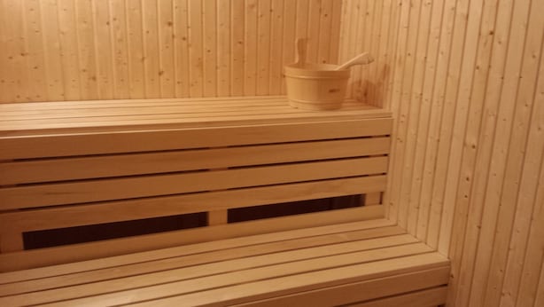 Um banco de sauna de madeira com um pequeno recipiente em cima.