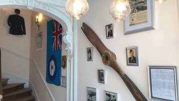 A staircase with a Union Jack flag, a wooden propeller, and several framed photographs on the wall.