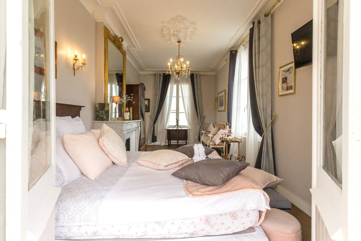 Un dormitorio elegante con una cama grande, una araña y una chimenea.
