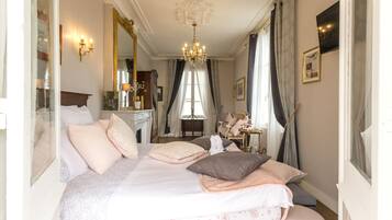 Een stijlvol ingerichte slaapkamer met een groot bed, een kroonluchter en een open haard.