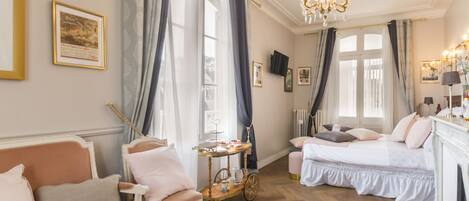 A cozy bedroom with a bed, a chair, a small table, and a chandelier.