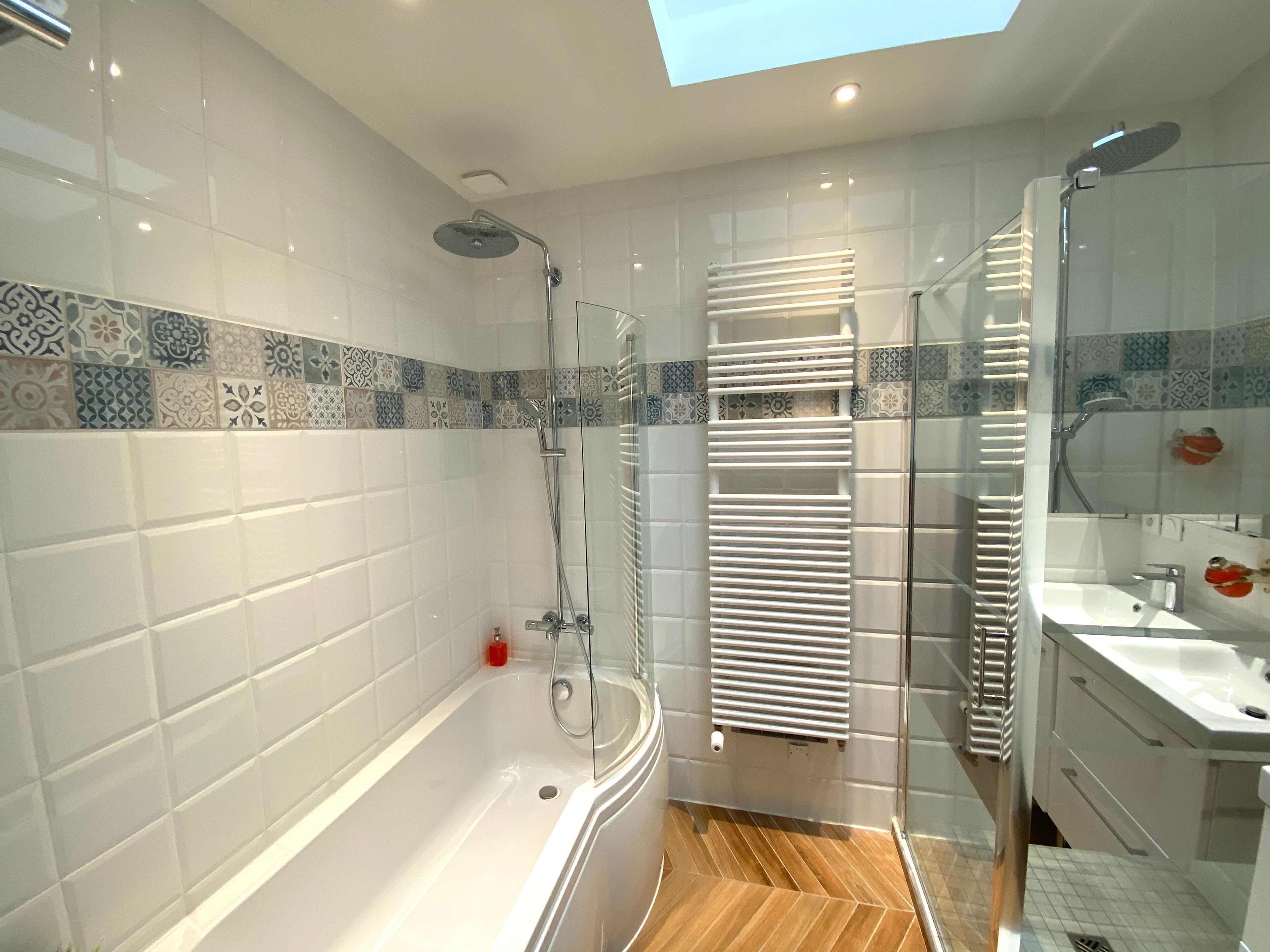 Un baño moderno con bañera, ducha y tocador con cristales.