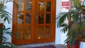 Entrada do Manor Hotel, com porta dupla de madeira, aviso indicando que não são permitidos animais de estimação e plantas em vasos.