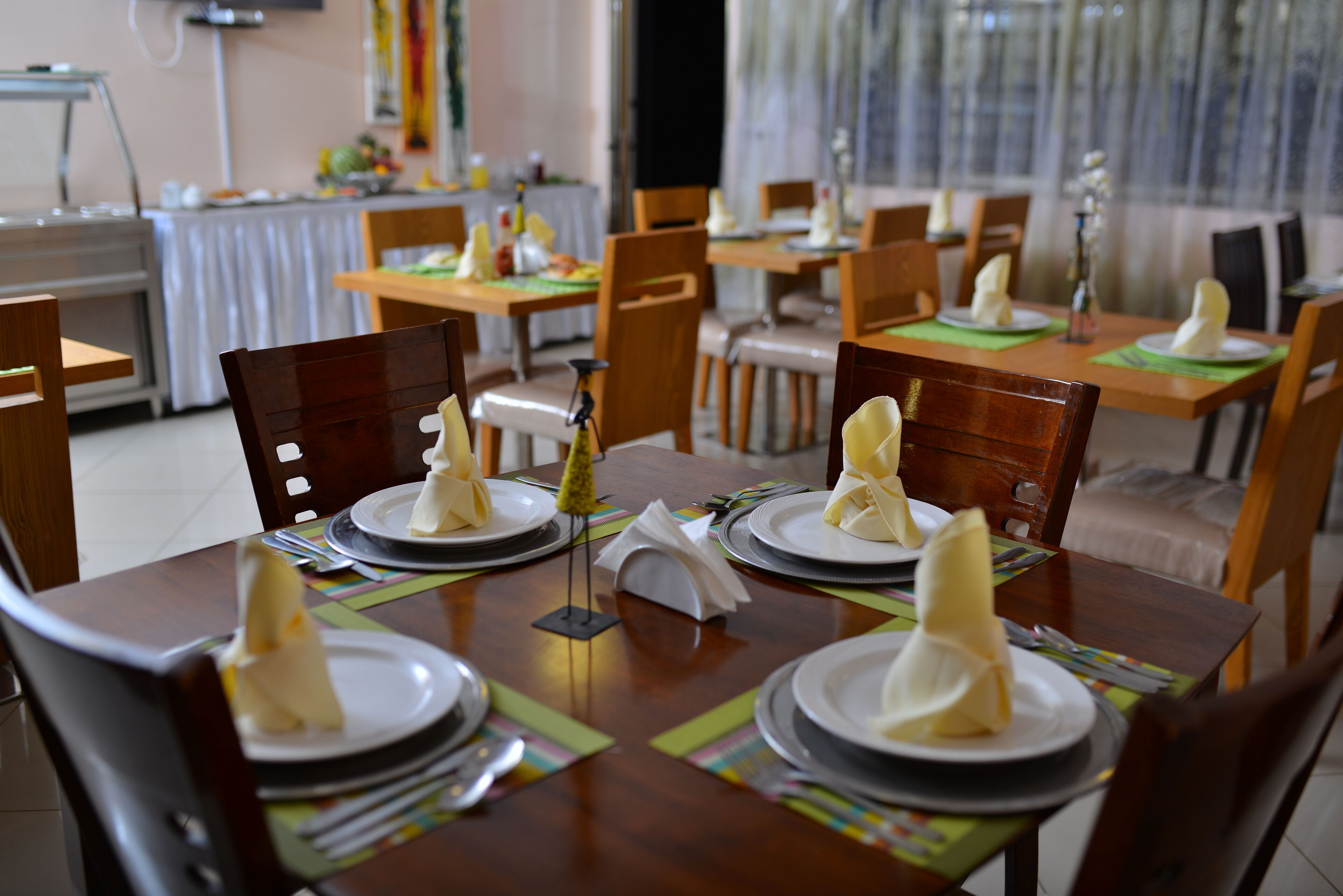 A dining area with multiple tables set for service, each with a folded napkin and a small decorative item on the center of the table.