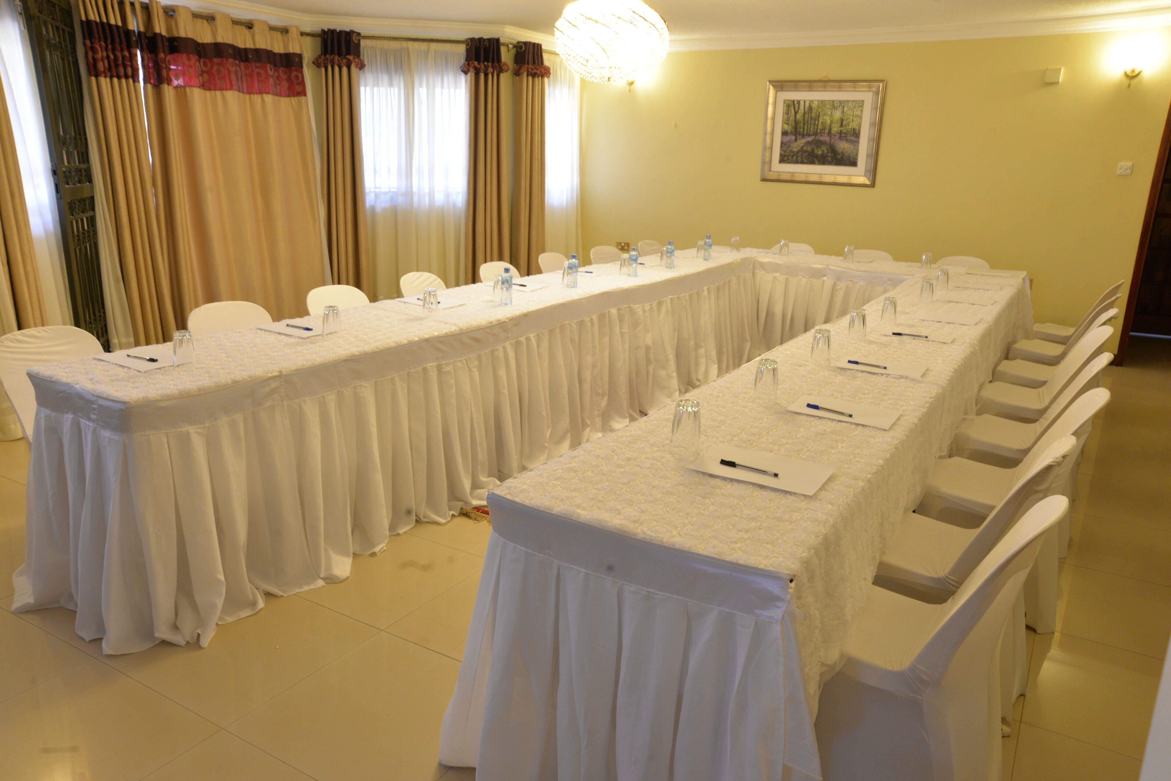 A conference room with a long table, chairs, water bottles, and a chandelier.
