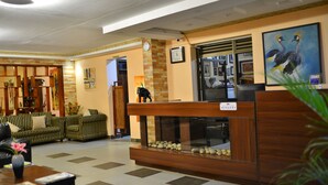 A reception area with a wooden reception desk, a seating area with striped sofas, and a decorative fish tank. - Royal Victoria House (Kampala)