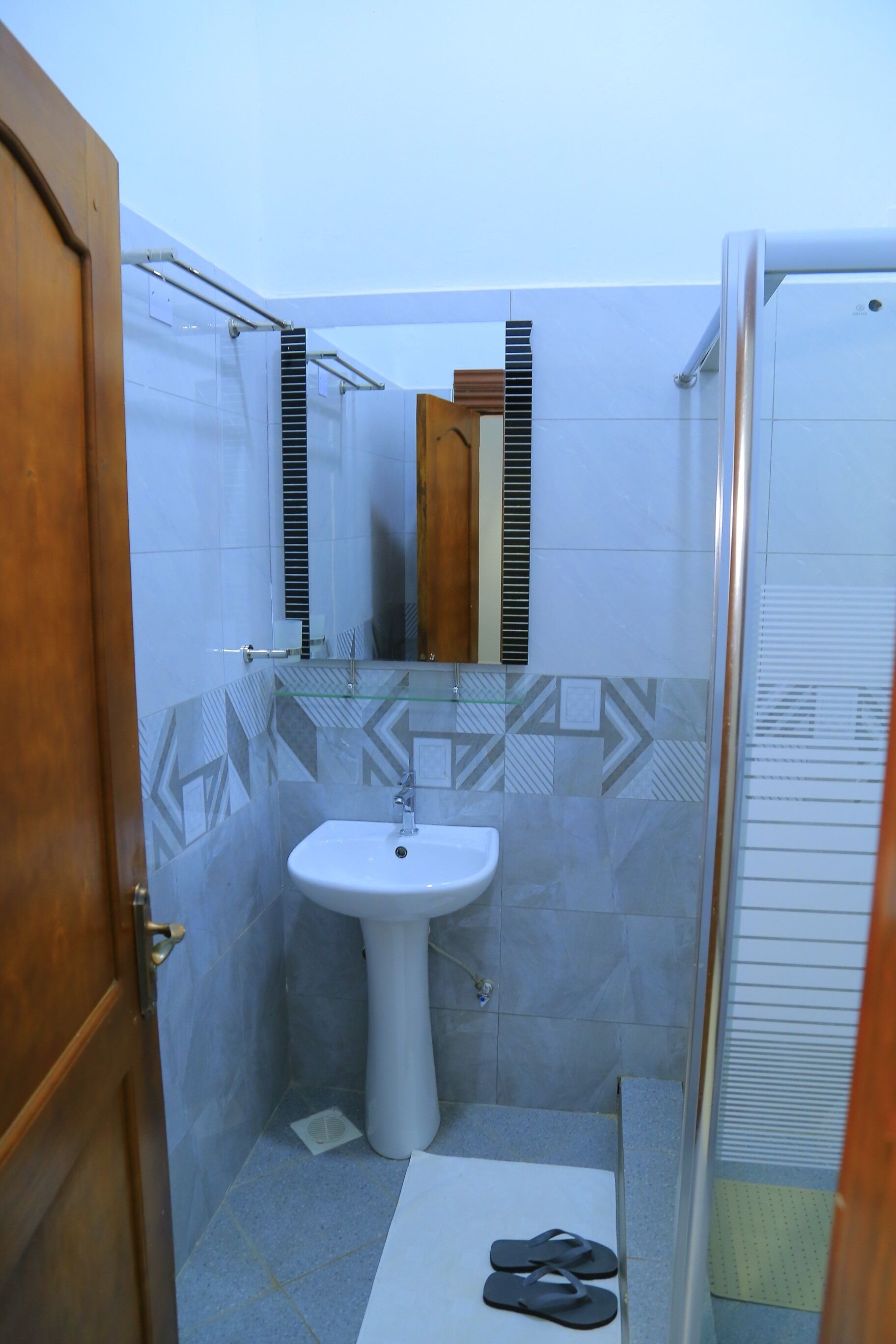 Une salle de bain avec un lavabo blanc, un miroir et un espace douche.