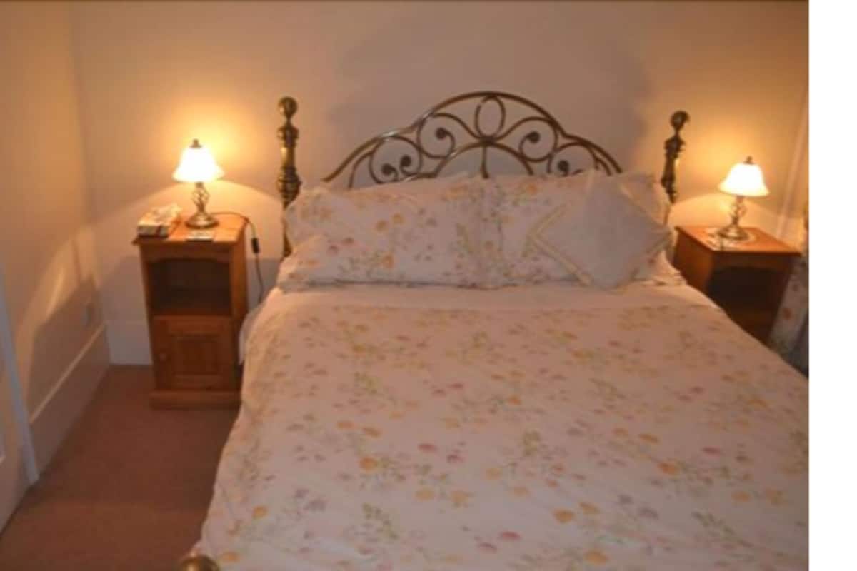 A bedroom with a floral bedspread, two bedside lamps, and a wooden nightstand.