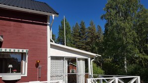 A red building with a white porch and a wooden deck. - Villa Mia (Vidsel)