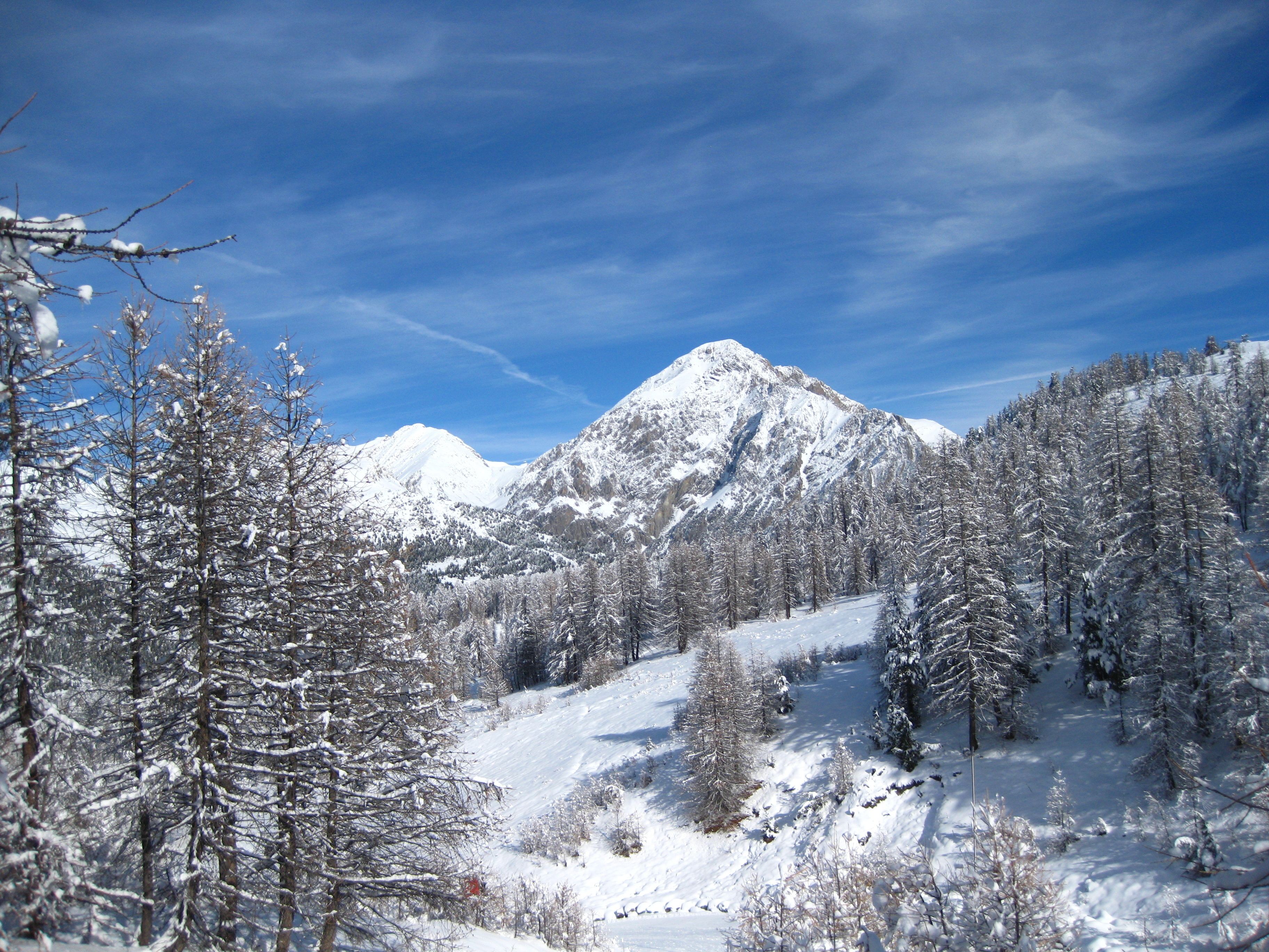 Un paysage de montagne enneigé, sous un ciel dégagé.