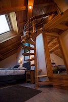 Une chambre de style « loft », avec un escalier en bois, un lit et une fenêtre.