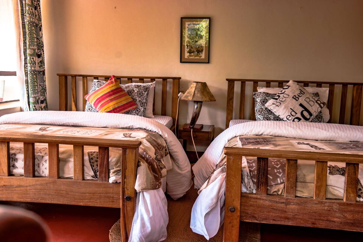 A bedroom with two wooden beds, each with patterned bedding and pillows.