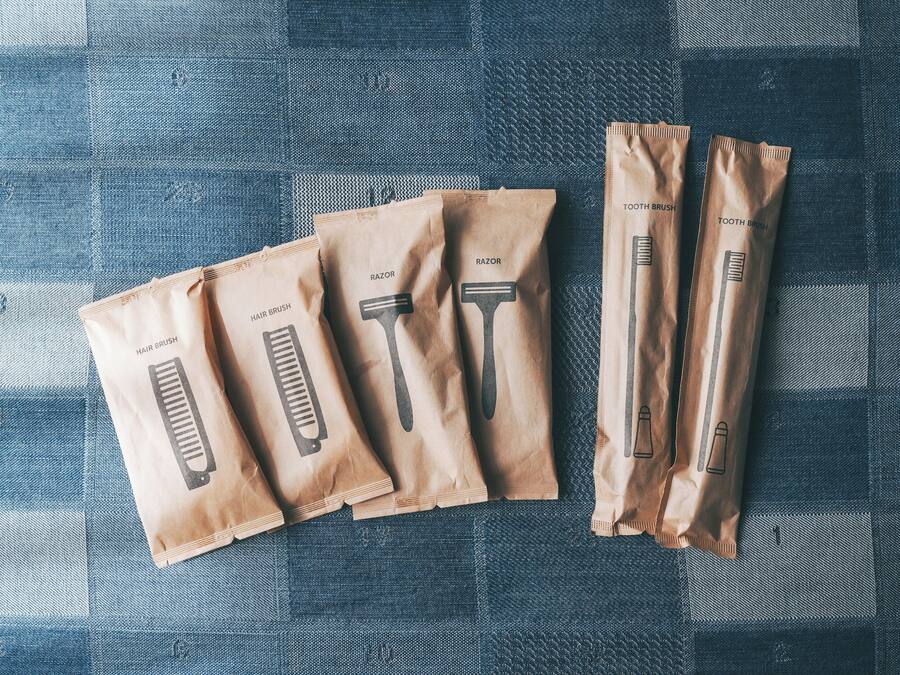 Five brown paper bags with different grooming tools labeled on them, placed on a checkered fabric surface.