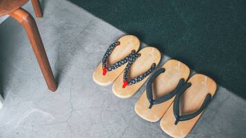 A pair of wooden flip-flops on a tiled floor next to a wooden chair.