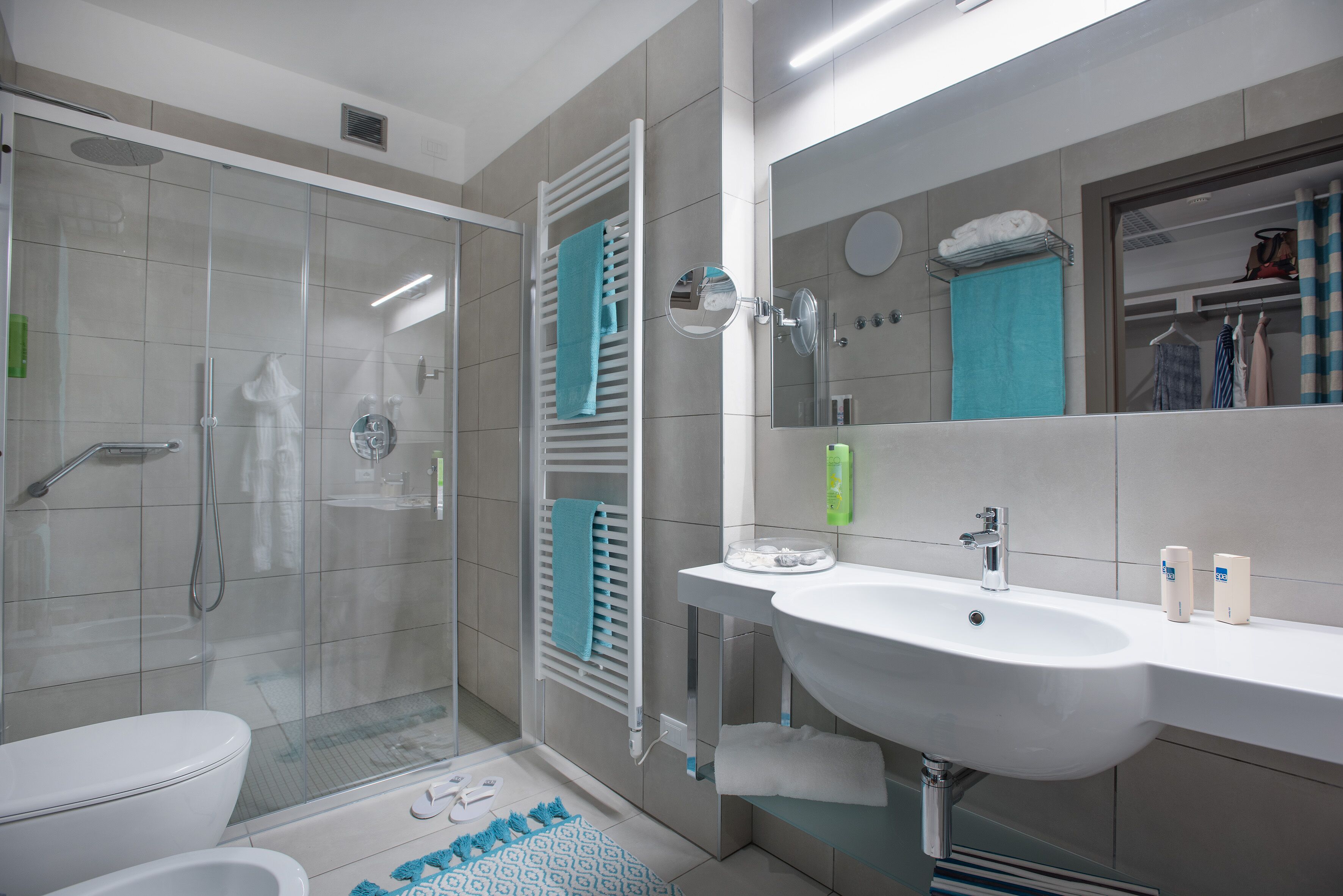 A modern bathroom with a glass-enclosed shower, a white sink, and a large mirror.