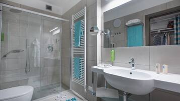A modern bathroom with a glass-enclosed shower, a white sink, and a large mirror.
