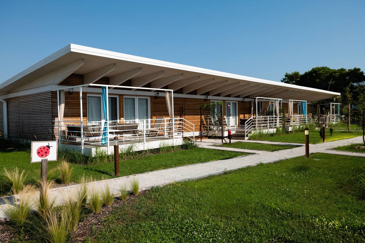 A modern building with a covered walkway, outdoor seating, and a sign indicating a bug-free environment.