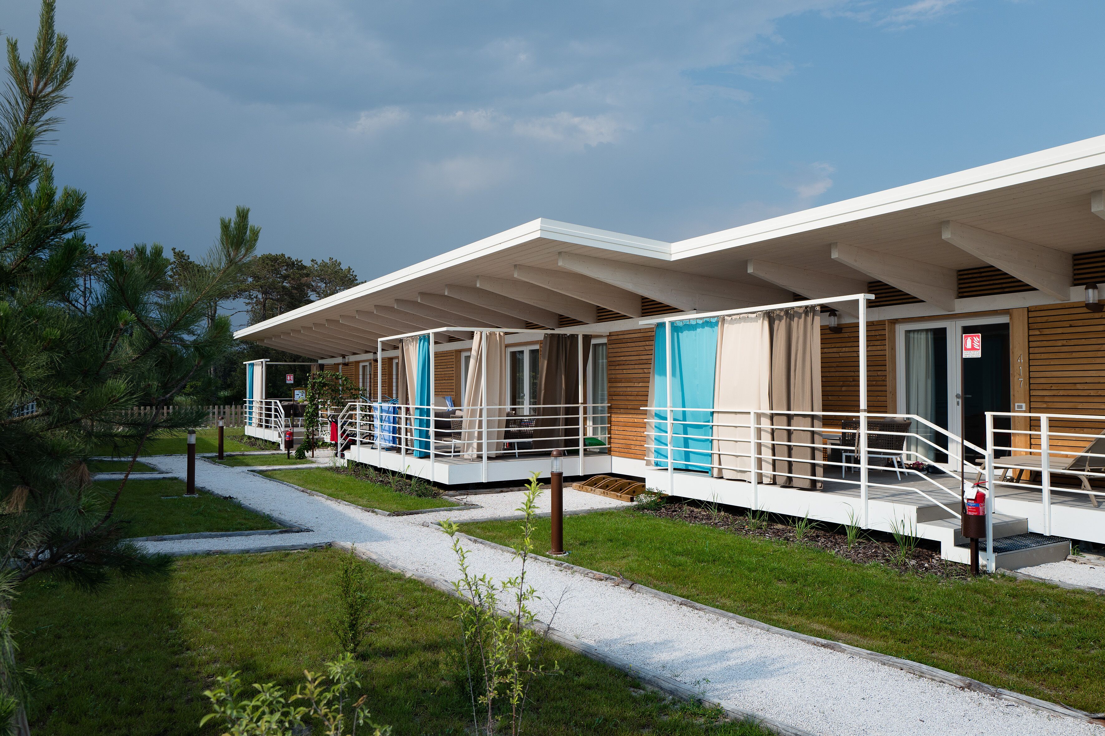 A modern hotel with a covered outdoor area, a gravel pathway, and a wooden deck.