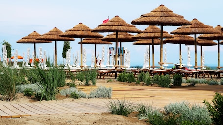 Am Strand, Liegestühle, Sonnenschirme, Strandtücher. Lino Delle Fate Eco Village Resort