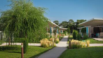 A pathway leading to a building with a covered entrance, surrounded by greenery and a clear sky.