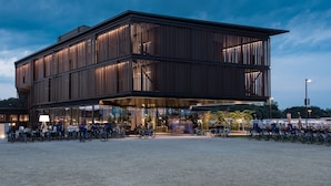 A modern building with a flat roof, large windows, and a covered outdoor area with bicycles.