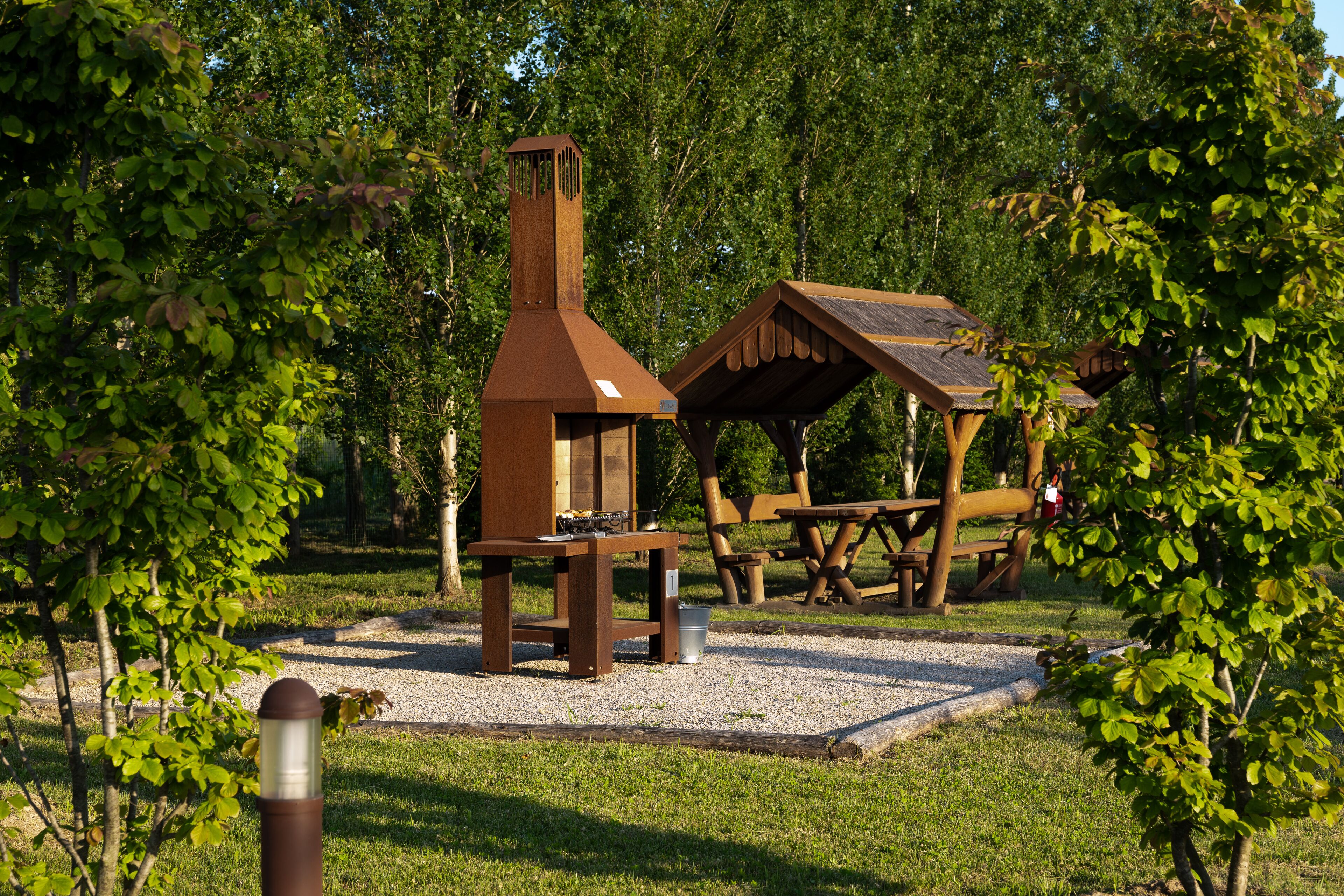 A rustic outdoor seating area with a chimney, wooden tables, and a picnic shelter.