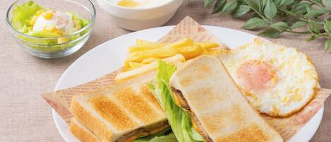 A plate with a sandwich, a fried egg, and fries, accompanied by a bowl of salad and a small bowl of sauce.