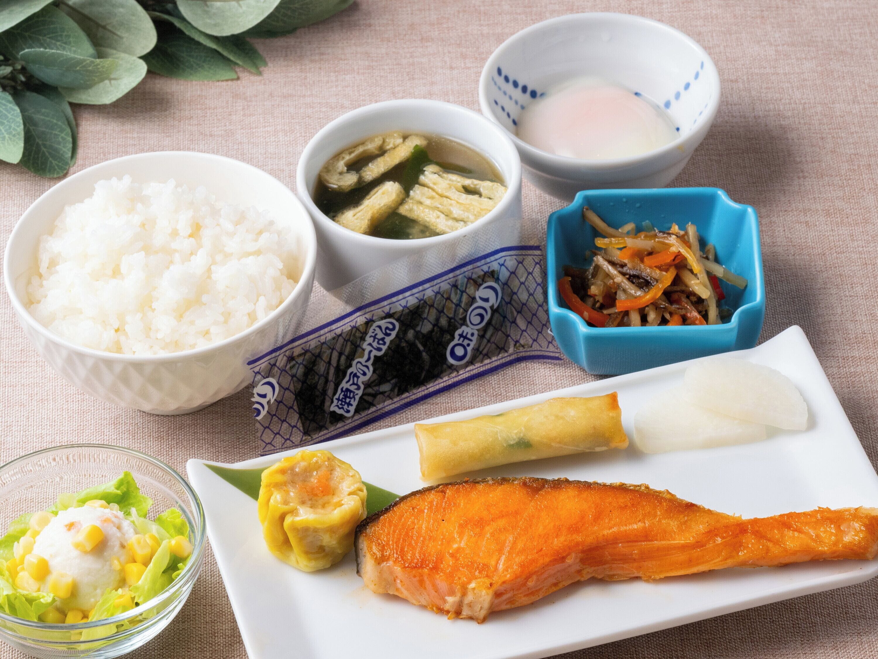 A meal with rice, soup, and fish on a white plate.
