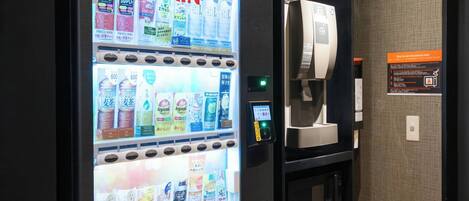 Máquina expendedora con diversas opciones de bebidas y un horno microondas.