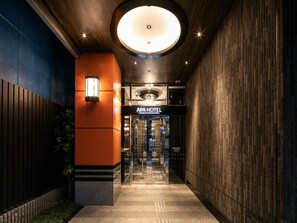 Ein Hotel Eingang mit modernem Design, mit einer Holzvertäfelung, einer Glasdoor und einem Schild mit der Aufschrift "APA HOTEL".