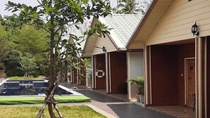 Un hotel con una galería techada, piscina y césped bien cuidado.