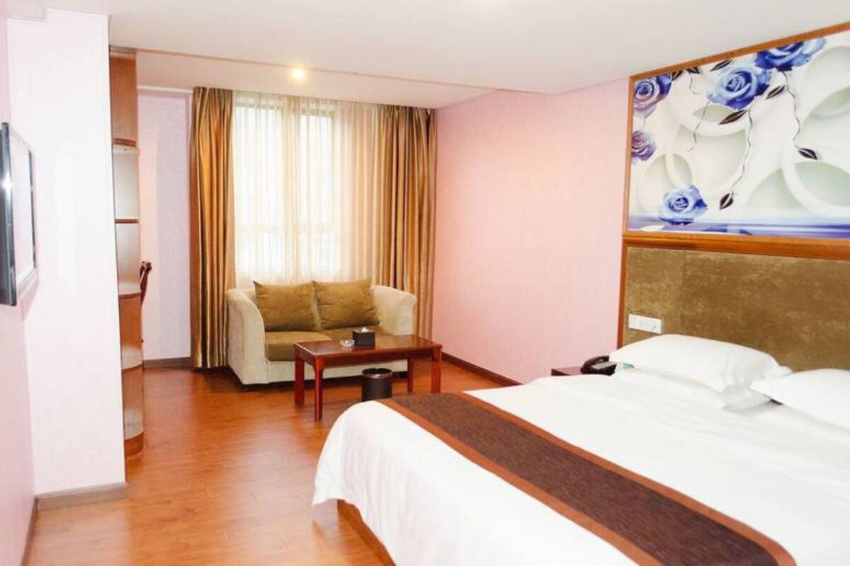 Una habitación de hotel con cama, sofá, una mesita y televisor.