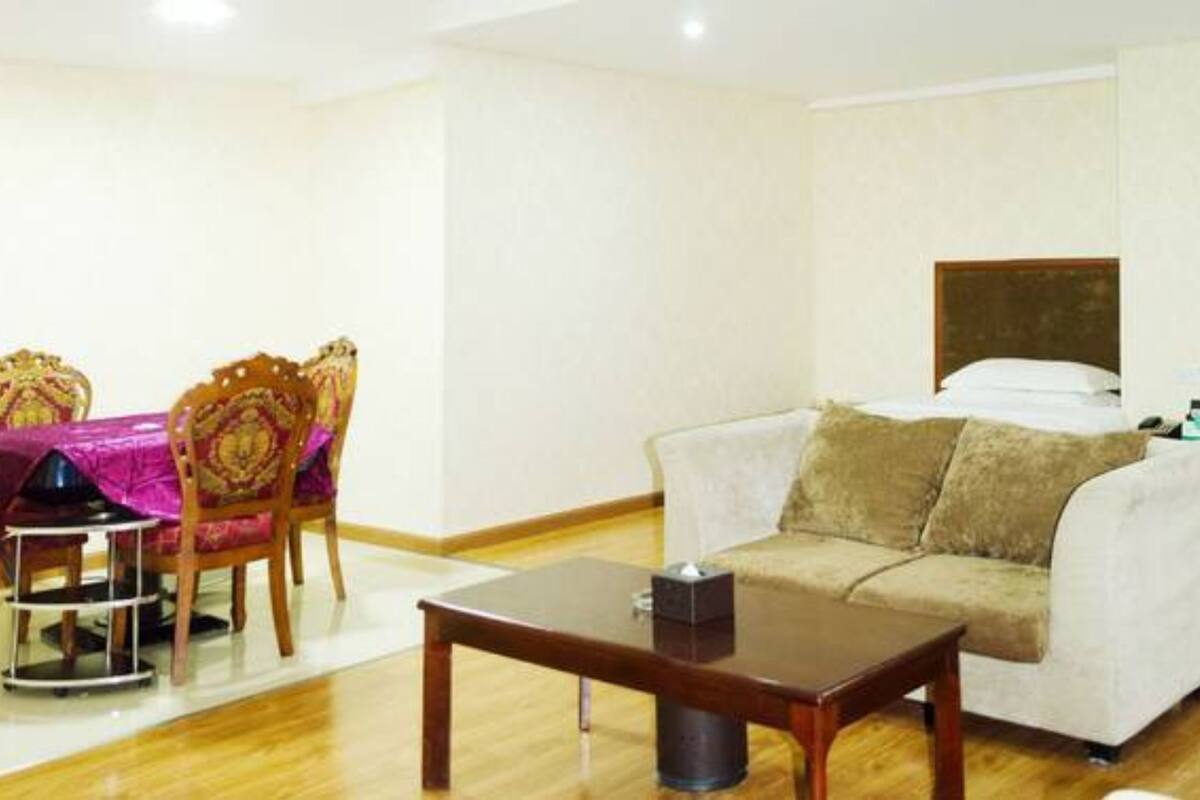 Una habitación de hotel con sofá, una mesa de comedor con sillas y una cama.
