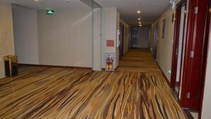A hotel corridor with patterned carpet, wooden doors, and a fire extinguisher. - Jintang Hotel Guangzhou (Guangzhou)