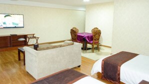 A hotel room with a sofa, a dining table with chairs, a TV, and two beds. - Jintang Hotel Guangzhou (Guangzhou)