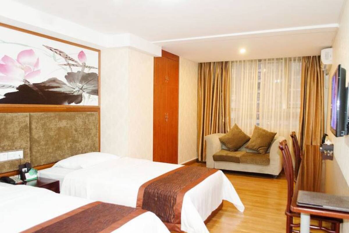 Una habitación de hotel con dos camas, un sofá, un televisor y un cuadro en la pared.