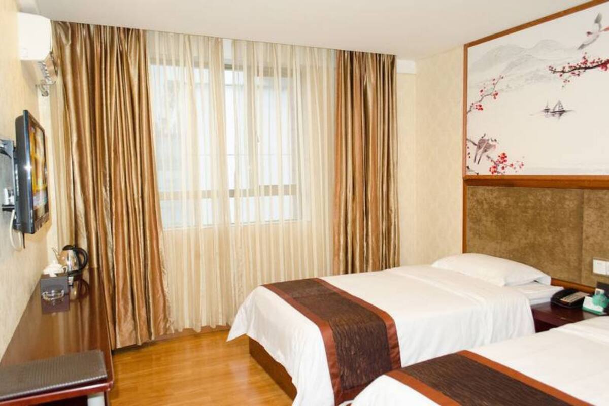 Una habitación de hotel con dos camas, un escritorio de madera, un televisor y un cuadro en la pared.