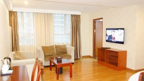 A hotel room with a sofa, a coffee table, a TV on a stand, and a wooden floor. - Jintang Hotel Guangzhou (Guangzhou)