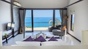 Un dormitorio moderno con una cama grande, un televisor y vista al mar.