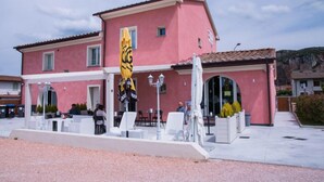 A pink building with outdoor seating and a yellow flag. - B&B Silvia (Vecchiano)