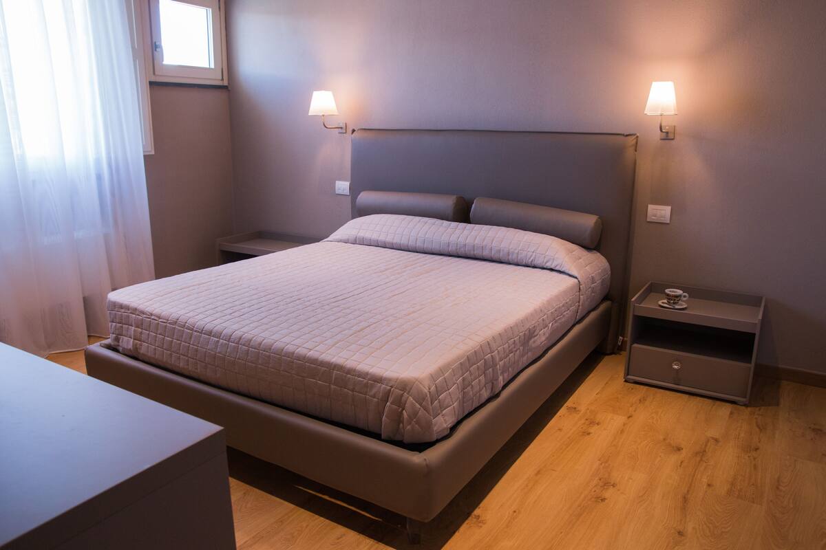 A neatly arranged bedroom with a bed, bedside tables, and a nightstand.
