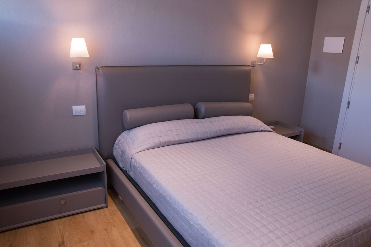 A modern bedroom with a bed, nightstands, and a built-in bench.