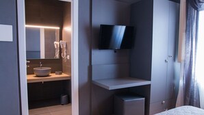A modern hotel room with a large bed, a TV mounted on the wall, a built-in sink, and a mirror. - B&B Silvia (Vecchiano)