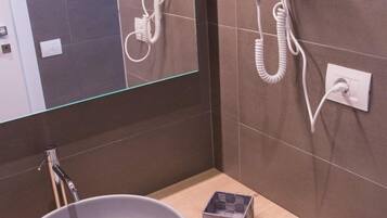 Un bagno con uno specchio grande, un lavandino rotondo e due asciugacapelli montati a parete.