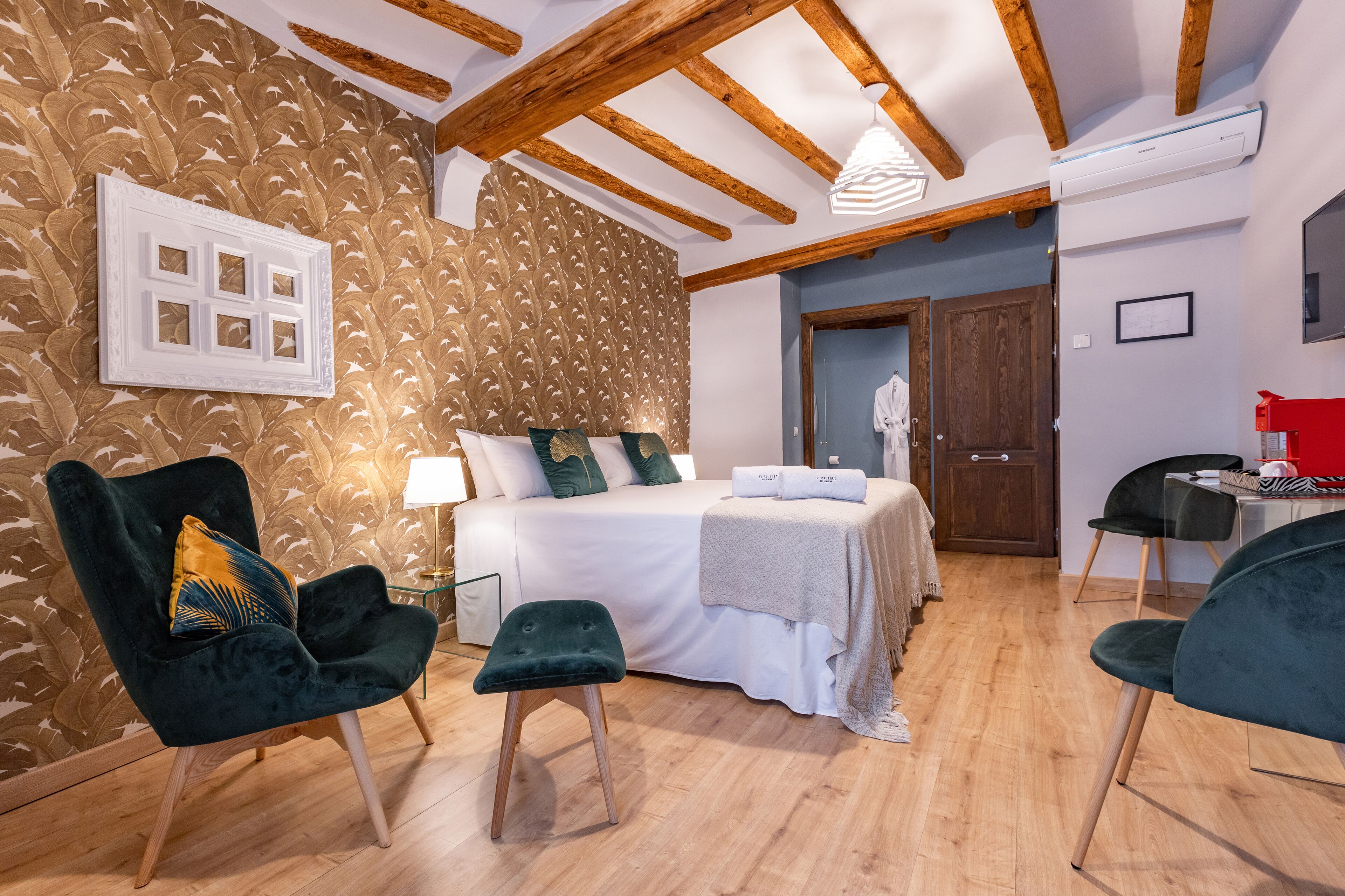 A bedroom with a bed, two chairs, a nightstand, and a wooden ceiling.