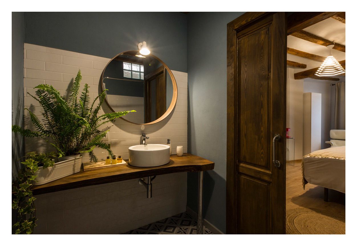 Un baño con un espejo redondo, lavamanos blanco y plantas en macetas.